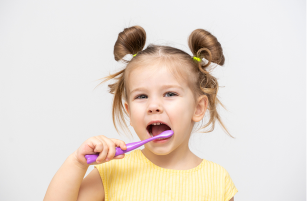 child in a yellow T shirt with clean teeth brushing
