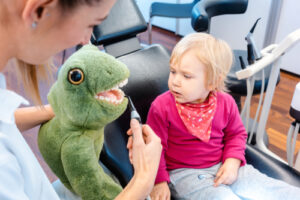 child in dentists surgery learning how to brush teeth with giant toothbrush