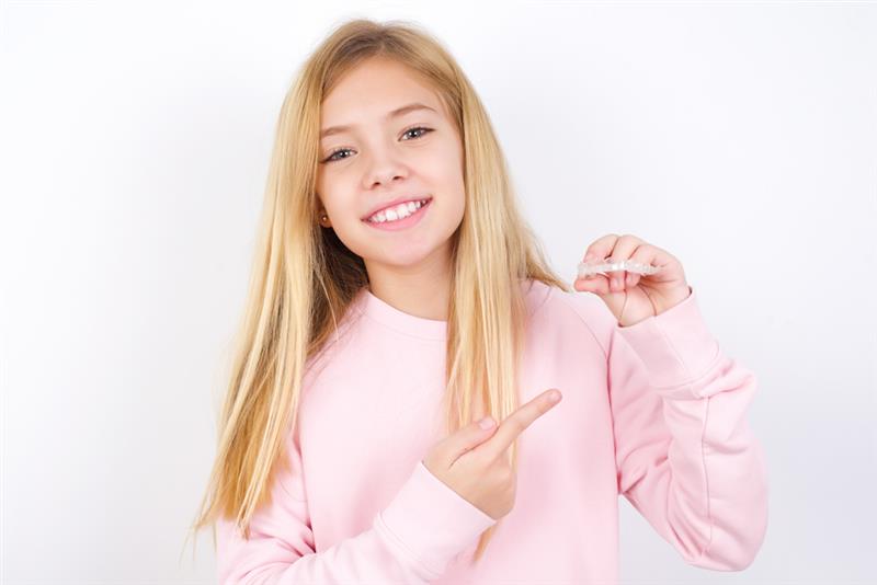 Confident teen showing Invisalign clear aligners with perfect smiles, ideal orthodontic solution for kids and teenagers
